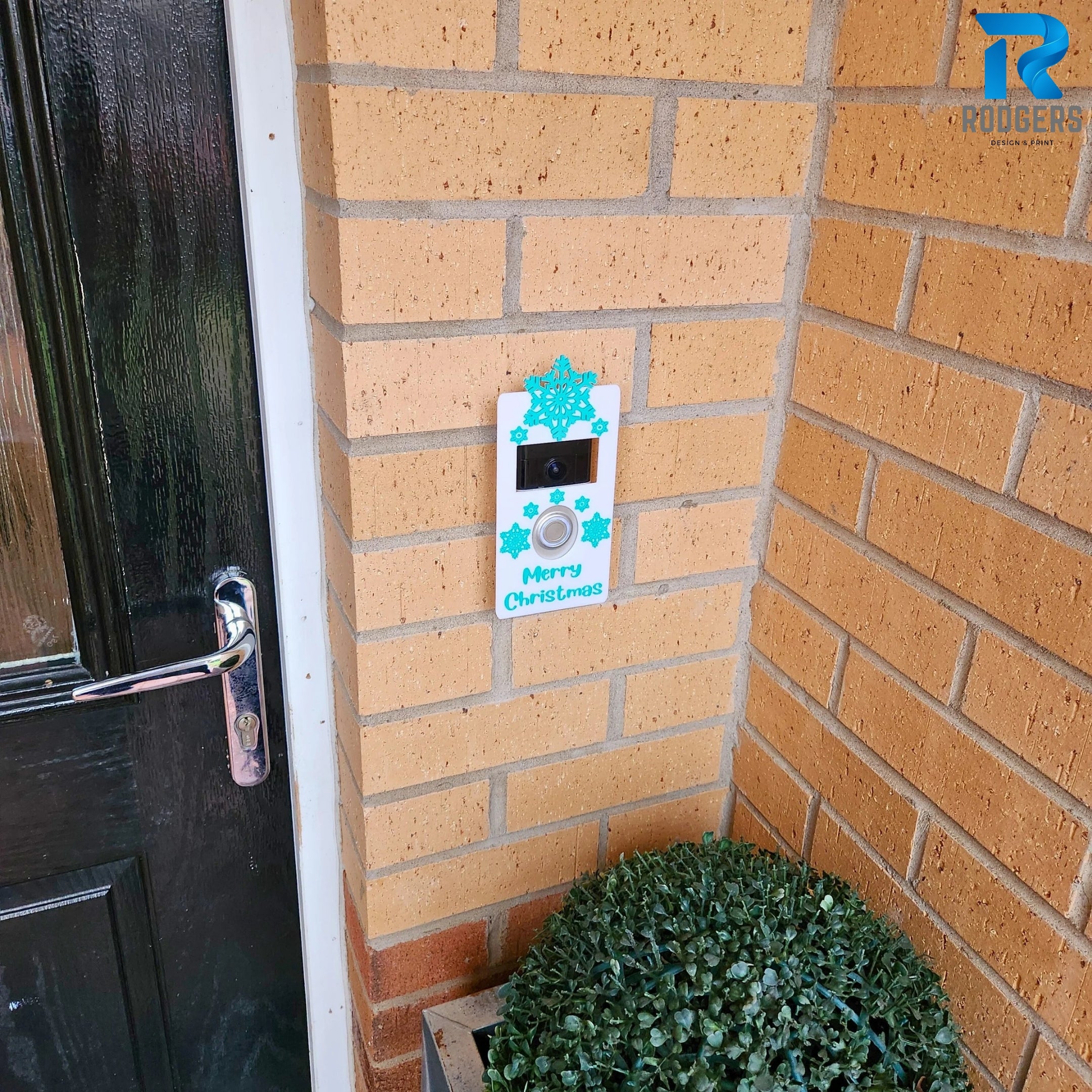 Festive Ring Doorbell cover featuring snowflakes, shown mounted on a door